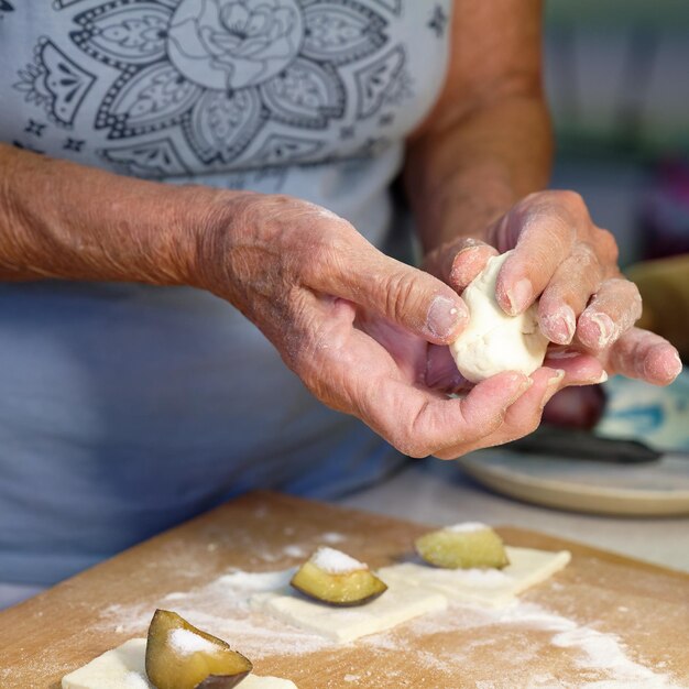 Preparazione di gnocchi di frutta fatti in casa con prugne specialità ceca di dolce buon cibo pasta sul tavolo di legno della cucina con le mani