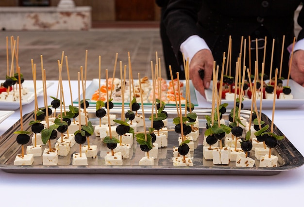 Preparazione di Sfiziosi antipasti con formaggio di capra morbido con olive e foglie di menta per la festa