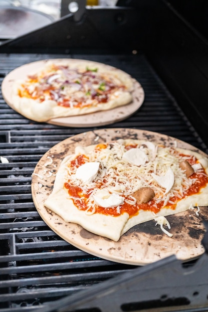 Preparazione di singole pizze alla griglia su una griglia a gas all'aperto.