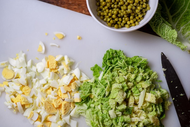 Preparazione di un'insalata vegetariana di verza Uova di gallina tritate e verza su un tagliere