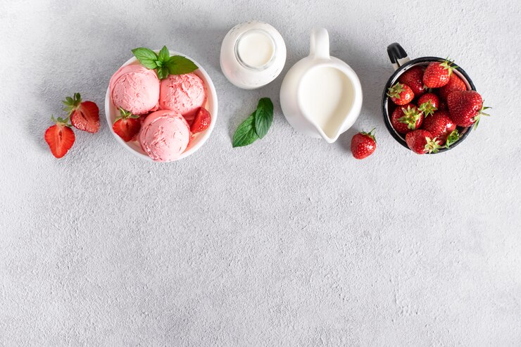 Preparazione gelato alla fragola. Ingredienti per fare il gelato. Ciotola di gelato, crema, fragole su uno sfondo di cemento, vista dall'alto.