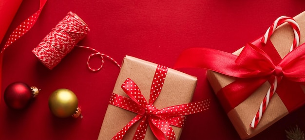 Preparazione natalizia Santo Stefano e festività regali di Natale carta artigianale e nastri per scatole regalo su sfondo rosso come strumenti di confezionamento e decorazioni regali fai-da-te come posa piatta per le vacanze