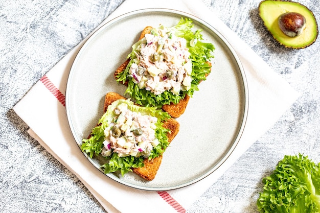 Preparazione passo dopo passo di un panino con tonno, avocado, cetriolo e cipolla