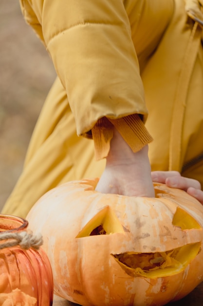 Preparazione per Halloween: la ragazza estrae i semi di zucca. Avvicinamento. Concetto di decorazione per le vacanze. La donna prepara jack-o-lantern. Festa di decorazione. Piccolo aiutante.