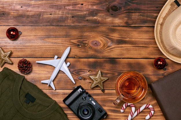 Preparazione per il concetto di viaggio - aereo giocattolo, macchina fotografica, tazza di tè, decorazioni natalizie su sfondo di legno.