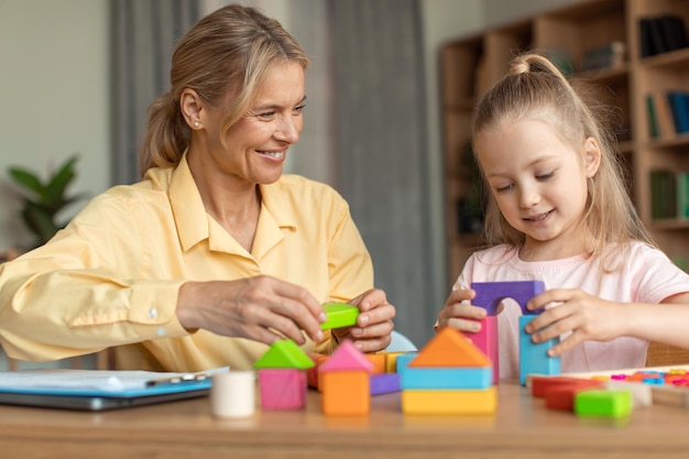 Preparazione per la scuola Bambina felice in età prescolare che gioca a giochi di legno in via di sviluppo con uno psicologo professionista