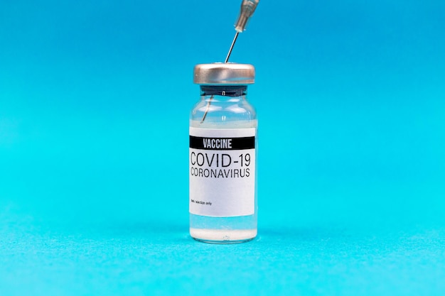 Preparazione per la vaccinazione, fiala di vaccino con siringa su sfondo blu, foto del concetto di immunizzazione COVID-19