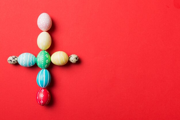 Preparazione per le vacanze Multi colori Uova di Pasqua su sfondo colorato La croce mostra il lato religioso e secolare della Pasqua Colore pastello Uova di Pasqua Concetto di vacanza con spazio di copia