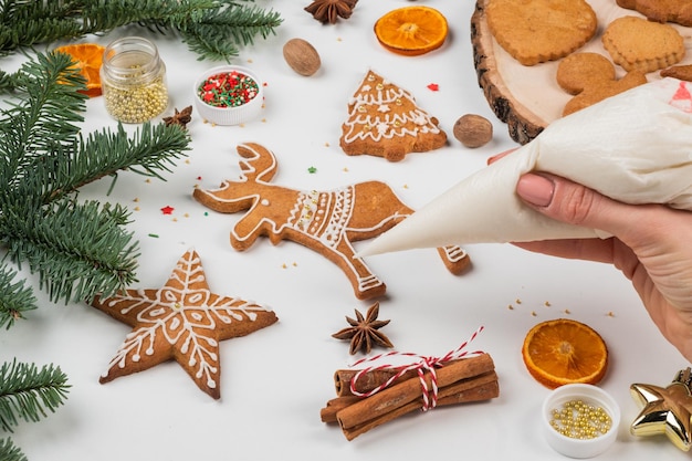 Preparazioni natalizie Le mani decorano il pan di zenzero di Natale fatto a mano con glassa di zucchero a velo Femal