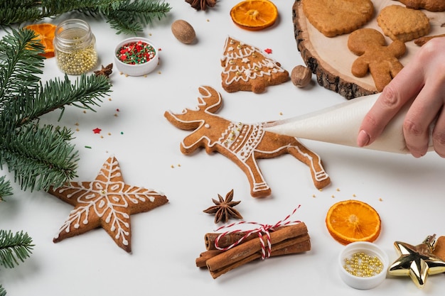 Preparazioni natalizie Le mani decorano il pan di zenzero di Natale fatto a mano con glassa di zucchero a velo Femal