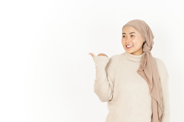 Presentando e indicando da parte con il pollice Bella donna asiatica che indossa l'hijab isolata su White