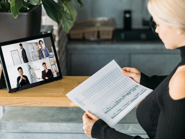 Presentazione video Telelavoro globale Donna che utilizza tablet che lavora da casa discutendo statistiche finanziarie report online con diversi team aziendali sullo schermo