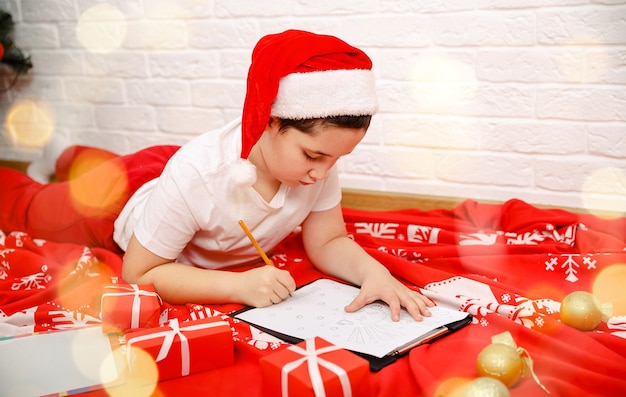 Presente lista dei desideri felice anno nuovo bambino ragazzo che scrive lettera a santa