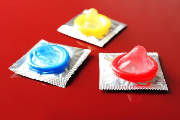 Preservativi aperti e avvolti su sfondo colorato Concetto di sesso sicuro