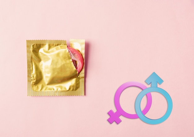 Preservativo per la salute sessuale mondiale o per la giornata dell'AIDS in confezione da imballaggio strappata e segni di genere femminile maschile