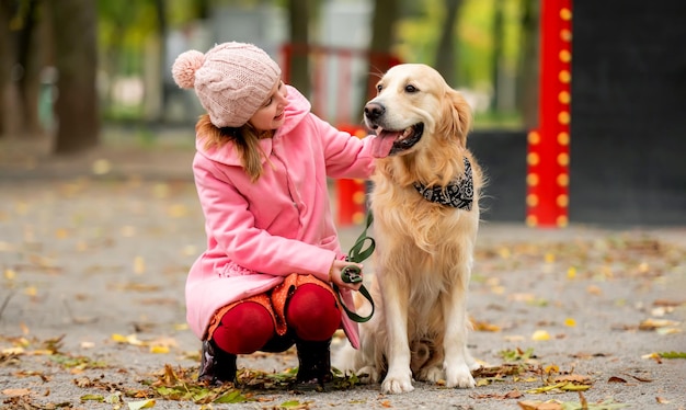 Preteen girl kid con golden retriever dog sitter nel parco e accarezzando doggy bambina con p