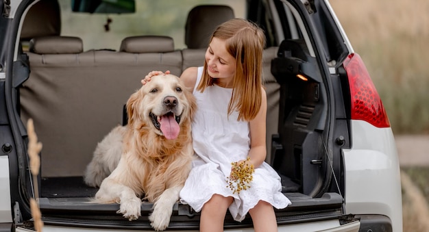 Preteen ragazza con cane golden retriever nel bagagliaio di un'auto