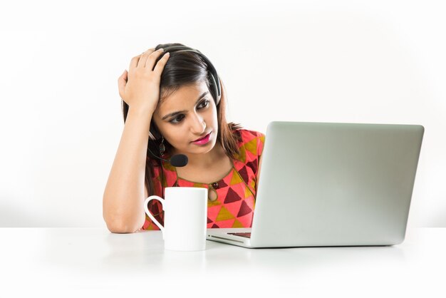 Pretty Indian Asian Girl o BPO o dipendente del Call Center che parla in cuffia con il laptop sul tavolo