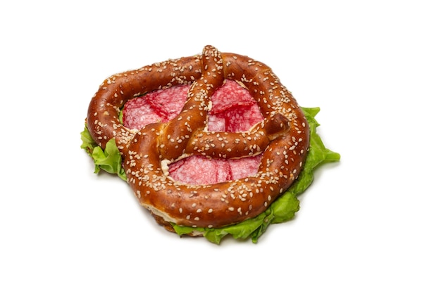 Pretzel con salame e lattuga isolato su uno sfondo bianco. Spuntino gustoso.