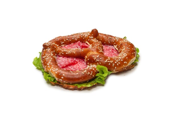 Pretzel con salame e lattuga isolato su uno sfondo bianco. Spuntino gustoso.