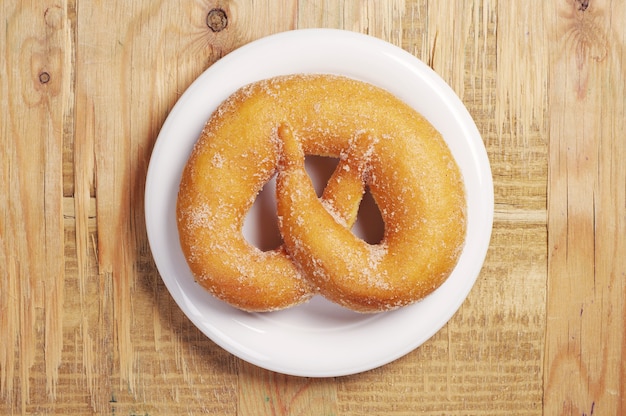 Pretzel dolce saporito in piatto su vecchio fondo di legno