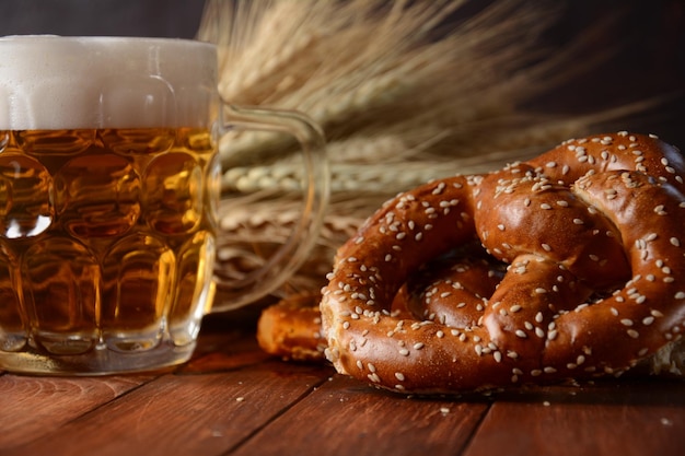 Pretzel morbido fatto in casa bavarese appena sfornato con birra Oktoberfest in stile rustico