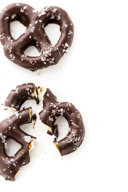 Pretzel ricoperto di cioccolato gourmet con sale marino su sfondo bianco.