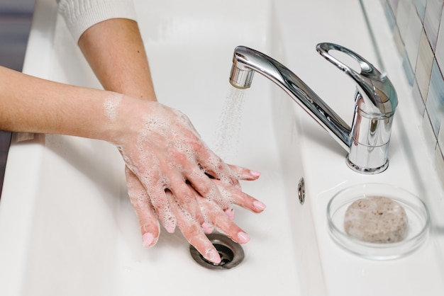 Prevenzione del coronavirus. Lavare le mani con sapone antibatterico, acqua corrente tiepida strofinando le unghie e le dita nel lavandino. Lavarsi le mani. Epidemic Covid-19. Prevenzione della malattia influenzale.