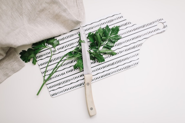 prezzemolo fresco verde con coltello e asciugamano da cucina sul tagliere vista dall'alto