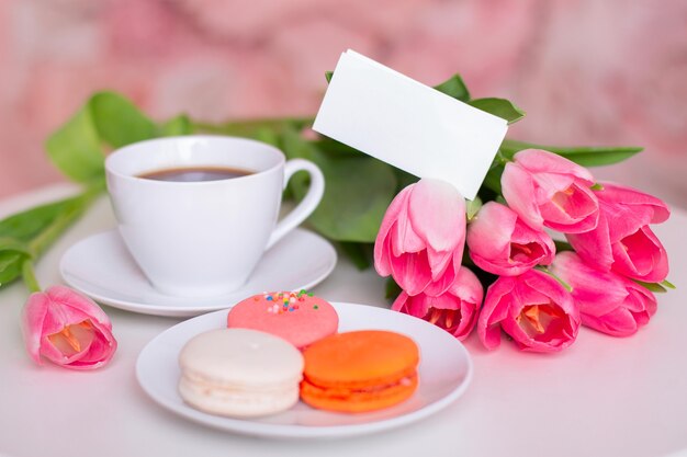 Prima colazione con tazza di tè, amaretti e tulipani rosa