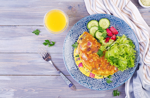 Prima colazione. Frittata con ravanello, cipolla rossa e insalata fresca sul piatto blu. Frittata - frittata italiana. Vista dall'alto