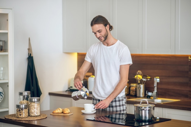 Prima colazione. Giovane uomo in homewear prepara la colazione in cucina