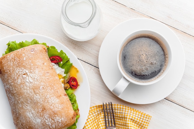 Prima colazione in stile rustico su una superficie di legno bianca. ciabatta con uovo in camicia e senape in grani con una tazza di caffè calda e fresca