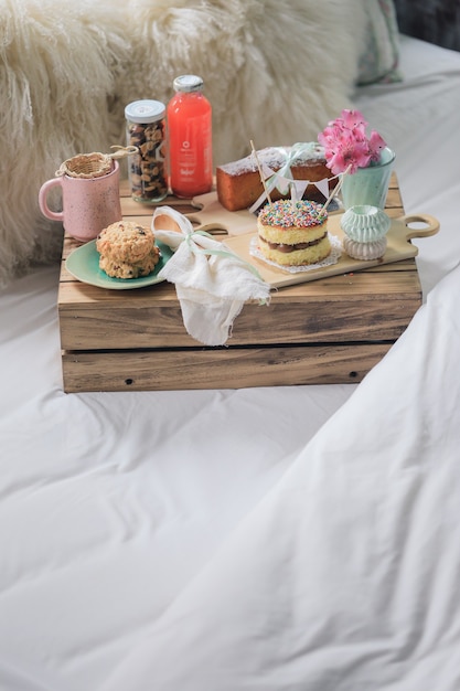 Prima colazione rustica di compleanno a letto con una mini torta, biscotti, tè e budino.