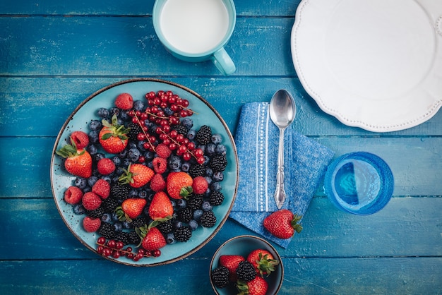 Prima colazione sana che mangia un mix di frutti di bosco freschi crudi