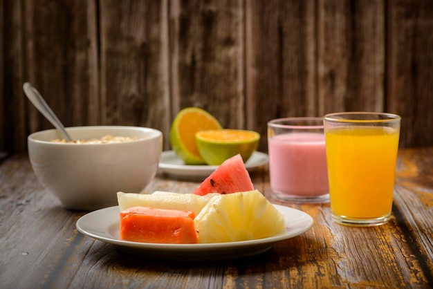 Prima colazione sana con frutta, avena e yogurt sulla tavola di legno.