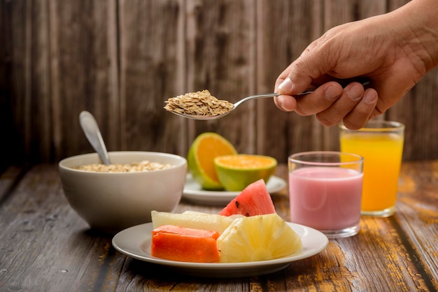 Prima colazione sana con frutta, avena e yogurt sulla tavola di legno.