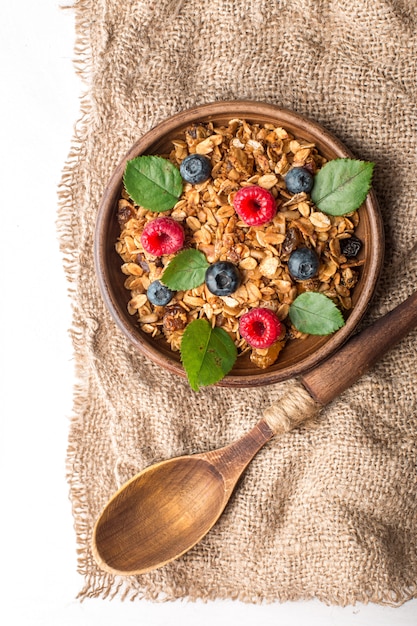 Prima colazione sana con granola e le bacche su fondo bianco.