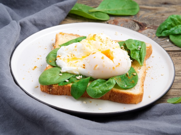 Prima colazione sana con pane tostato e uovo in camicia con insalata verde, spinaci. Vista laterale.