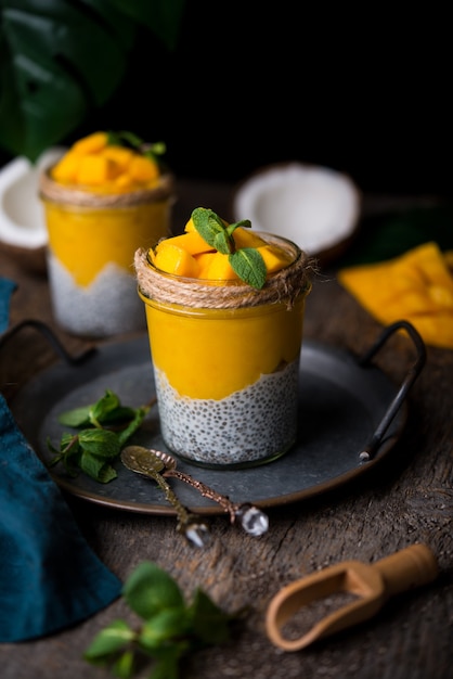 Prima colazione sana fatta in casa, budino di chia con latte di cocco e mango su un tavolo di legno