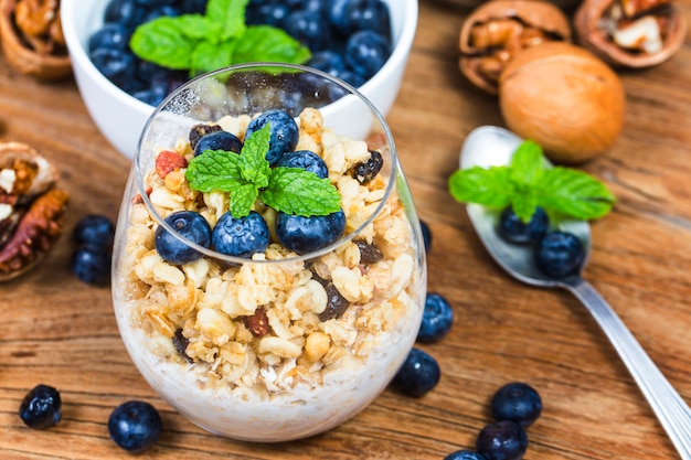 Prima colazione sana: granato di avena con yogurt e mirtilli freschi su fondo in legno