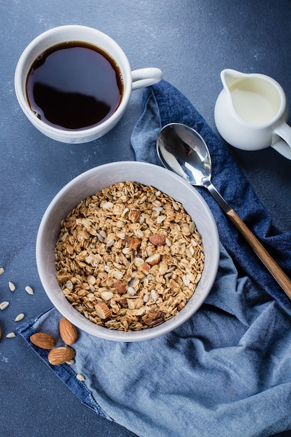 Prima colazione sana - muesli, latte o yogurt e miele sul vassoio di legno sul fondo di pietra della tavola.