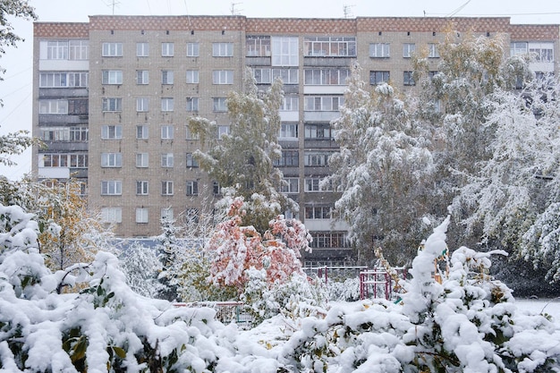 Prima neve sui rami degli alberi e sulle foglie autunnali delle strade della città