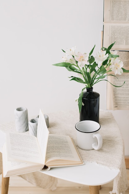 Primavera ancora in vita. Colazione a letto. Camera da letto bianca. Dolce casa. Libri, fiori e tazza di caffè. laici piatta