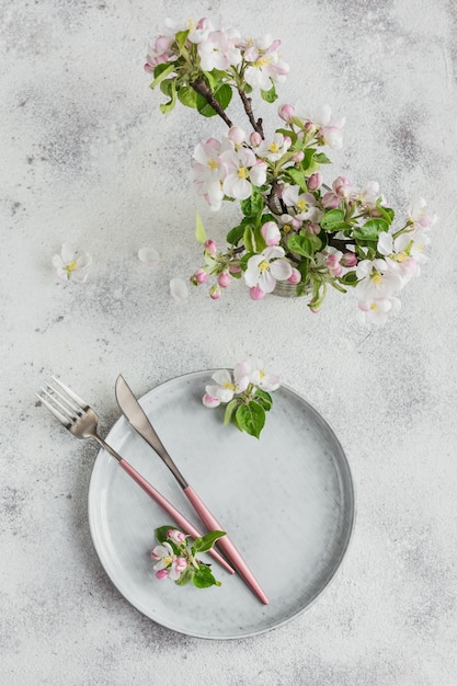 Primavera posto tavola con rami di melo in fiore e fiori sul tavolo luminoso. Decorazione di feste in stile provenzale. Cena romantica. Sovraccarico con copia spazio per il testo