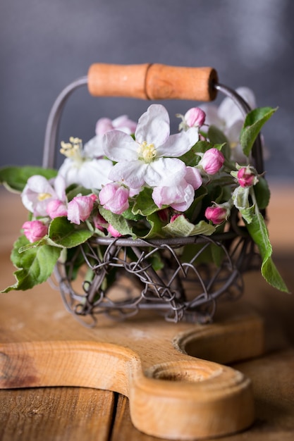 Primavera. rami di un melo in fiore in un cesto su uno sfondo di legno