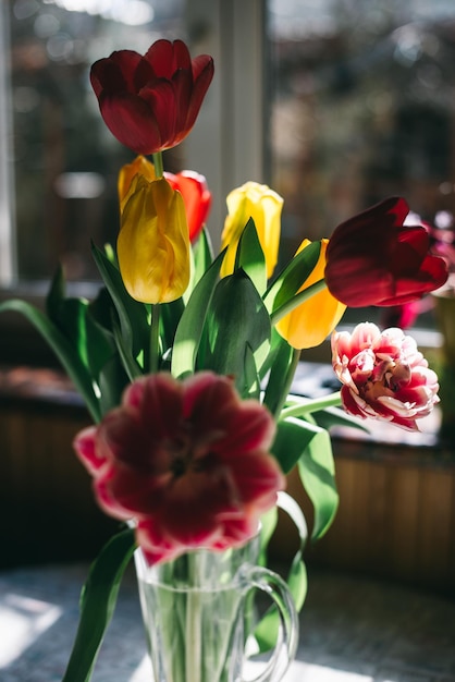 Primavera tulipani in un vaso su un tavolo illuminato dal sole