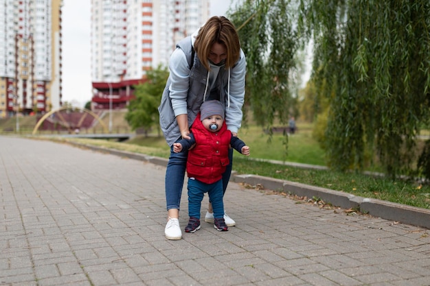 Primi passi di un bambino della mamma durante una passeggiata in strada