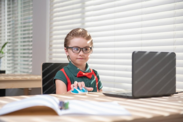 Primo giorno a scuola. Simpatico bambino che utilizza il computer portatile, studiando il computer.