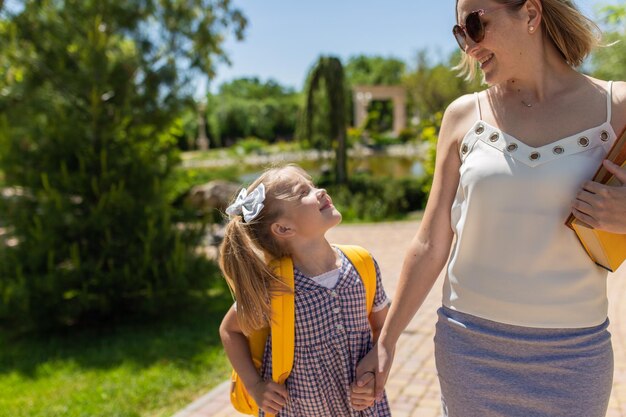 Primo giorno di scuola, la madre guida una bambina in prima elementare